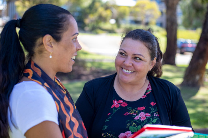 Two aboriginal women having a discussion amidst natural surroundings