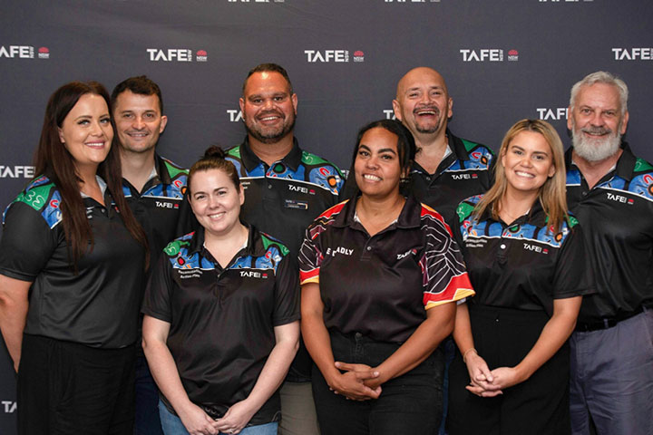 Eight Indigenous staff members stand together at TAFE NSW.