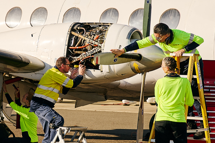 Aviation mechanic teacher guiding students as they work on a plane engine