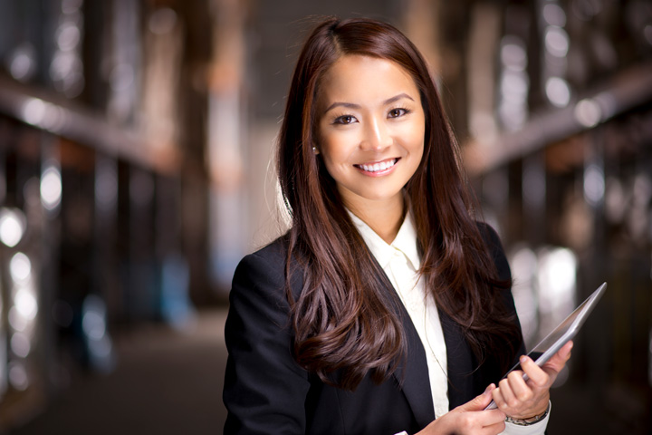 A businesswoman smiles at the camera while holding a tablet.