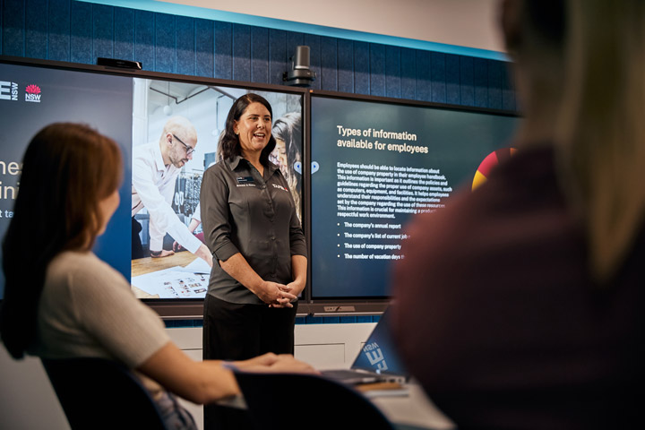 Presenter in a business administration setting showing a pie chart and a slide titled 'Types of information available for employees' to an audience.