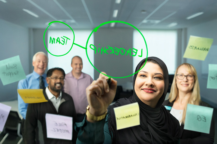 A woman wearing a hijab leads a brainstorming session with her colleagues.