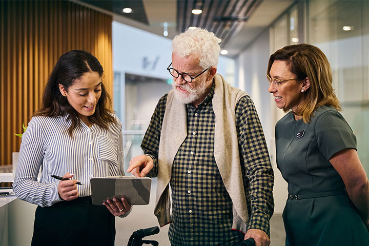 A young woman assists an elderly man with completing paperwork.