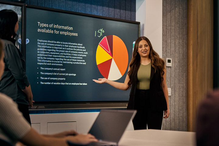 A business student confidently presents to her classmates and teacher.