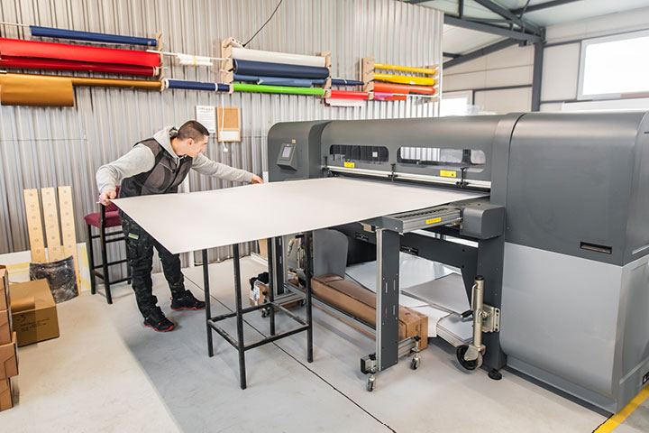 A person operates a large, high-end industrial printer.
