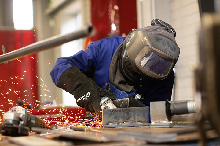 A young student welding in a workshop