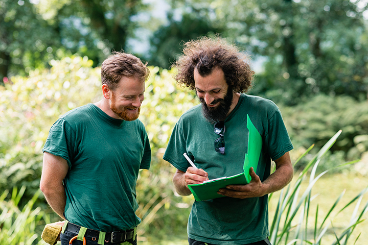 Two male landscapers attentively reviewing a landscaping project.