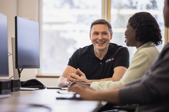 A male ɫֱstaff member and a female student are seated at a desk, focused on a computer screen and engaged in a collaborative task.