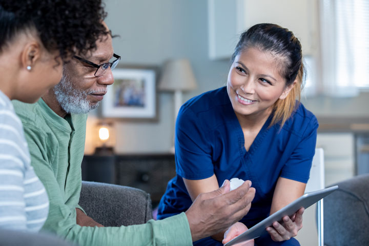Nurse engaging in friendly conversation with elderly patient.