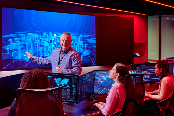 Control room with multiple operators monitoring 3D city map projections