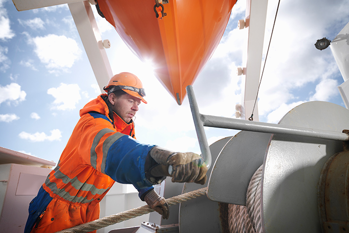 Sailor in working clothes working on the deck of a ship.