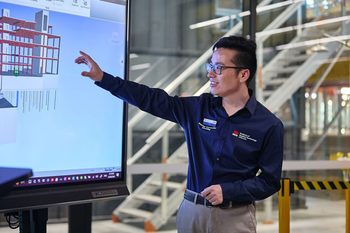 A TAFE NSW teacher, dressed professionally and wearing black glasses, presents an introduction to Building Information Modelling (BIM) at the Institute of Applied Technology – Construction (IATC).