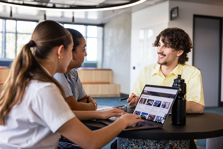Two careers advisers and a student discussing career options at a table, with a laptop open.