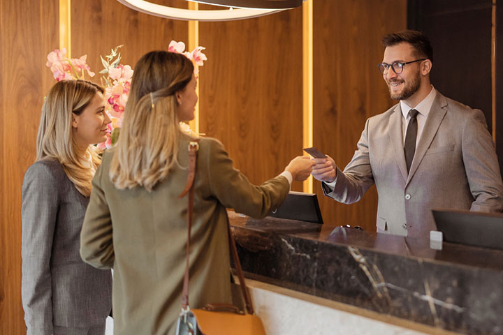 Hotel receptionist checking in two customers.