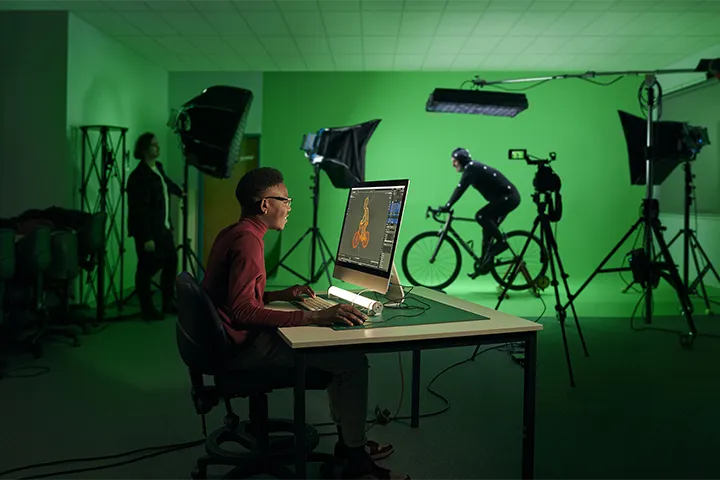 A student works on an animation project at a computer, surrounded by sketches and digital tools.