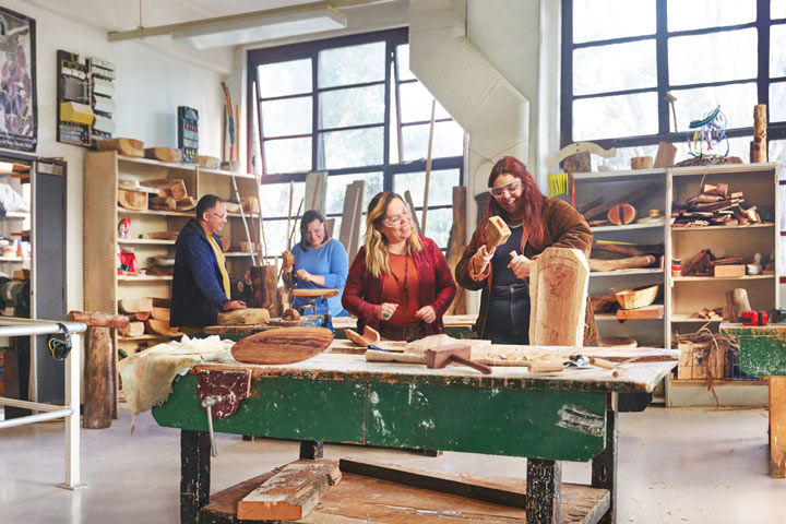 A female Aboriginal teacher guides a young student working on a sculpture project.