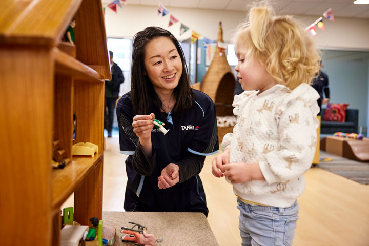 Early childhood education teacher engaging with young child in classroom.