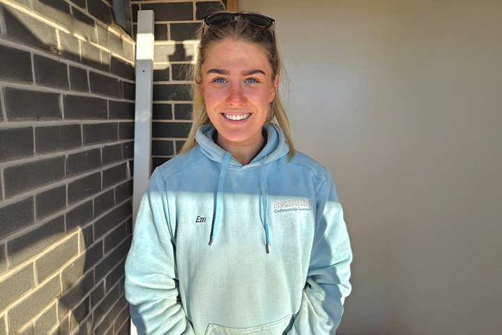 Emily Blasig in work clothes, smiling at the camera.