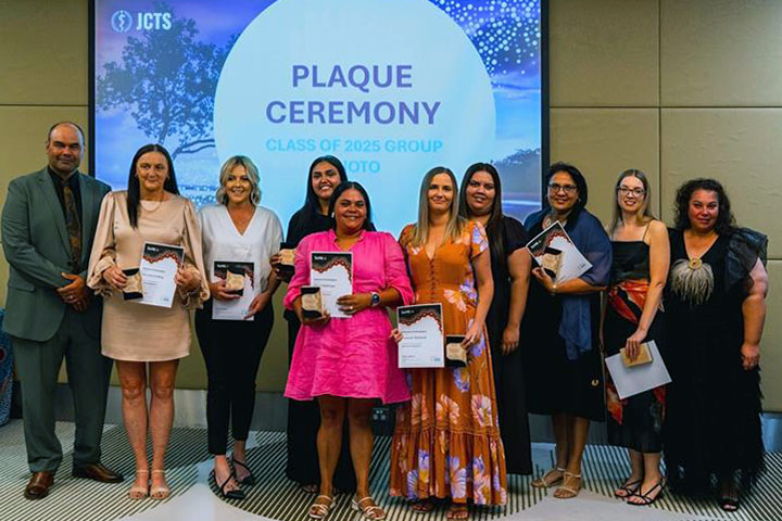 Graduates from the TAFE NSW and Joint Colleges Training Services program stand together at their graduation, holding their certificates and awards. 