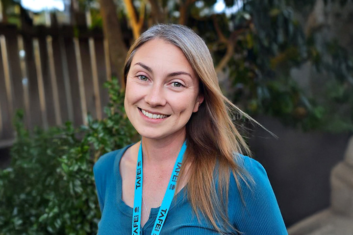 TAFE NSW student Jamie-Lee Scotts smiles at the camera, wearing a blue TAFE NSW lanyard around her neck.