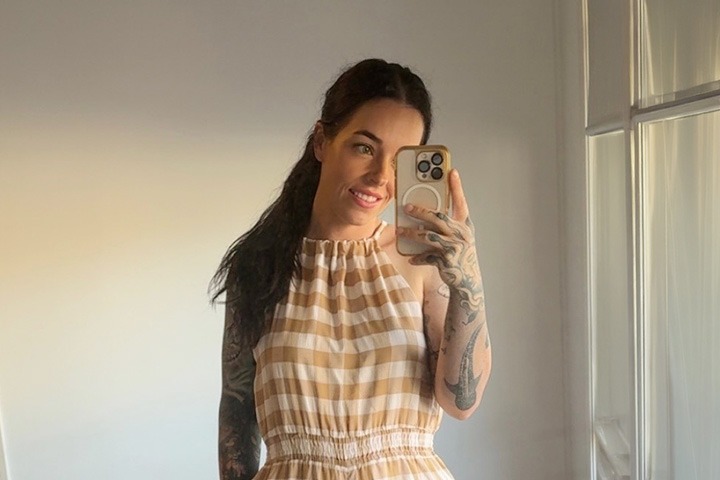 TAFE NSW trainee, Kara Bates, smiles while holding her mobile phone.