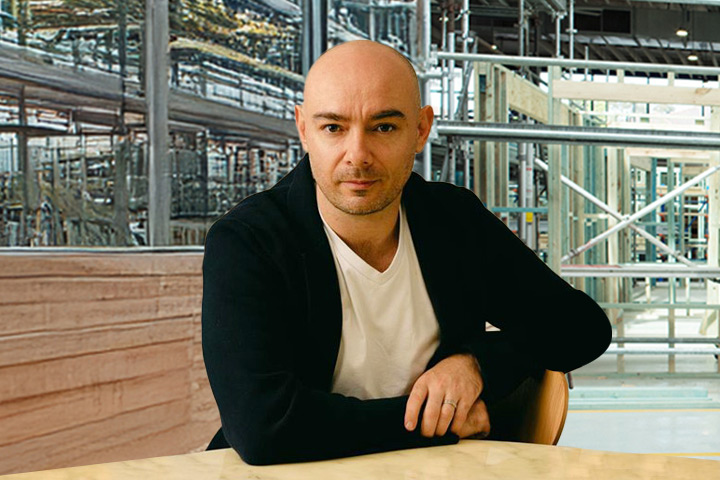 Jason sits casually at a desk in a construction warehouse. 