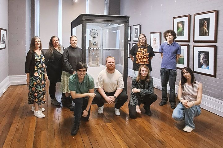 TAFE NSW students standing and kneeling amongst art in the MUSE Gallery