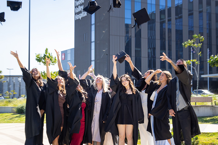 A group of graduates joyfully throwing their caps into the air, celebrating their academic achievements together.