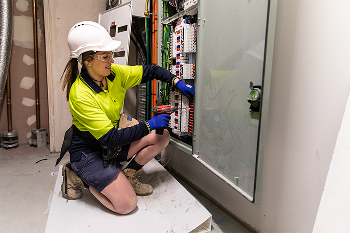 A woman dressed in high visibility wear repairs an electricity grid