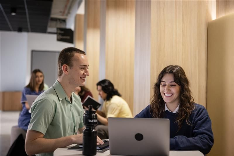 A male and female student working on laptops