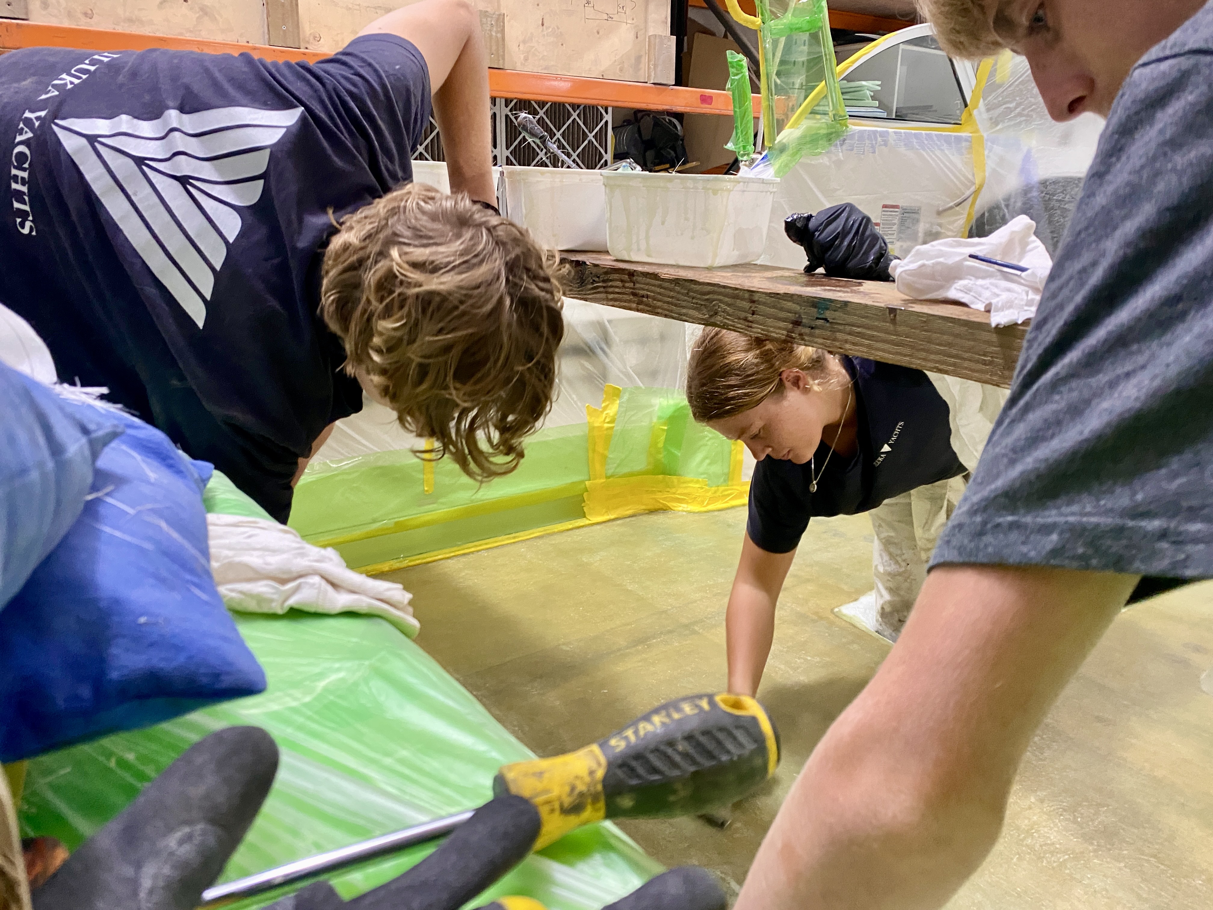 Talia Dunning, a Certificate III in Marine Craft Construction graduate, works closely alongside two other colleagues.