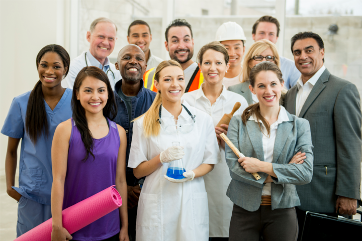 A group of people all dressed in different work uniforms standing together smiling at the camera.