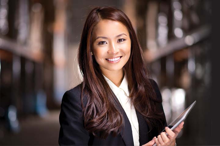 Young professional woman in a suit, holding a tablet.
