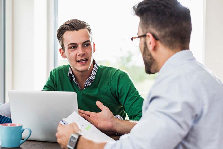 Colleagues in conference room, one with laptop open.