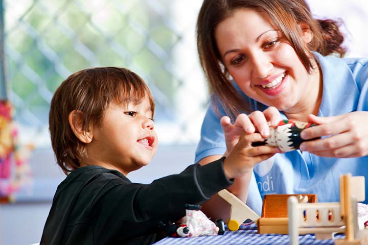 Female teacher and young child smiling during arts and crafts activity.