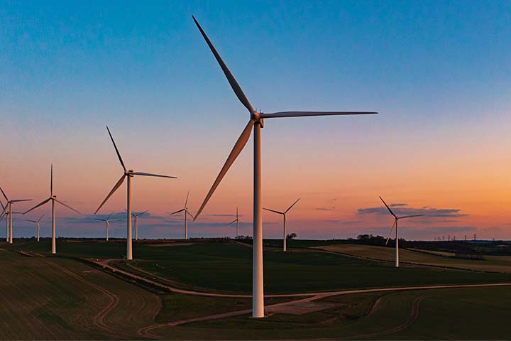 Wind turbines in a field during a colorful sunset.