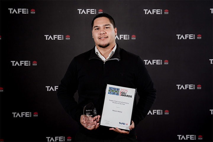A person holding a transparent award and a certificate in front of a TAFE NSW backdrop. The certificate reads: “2025 Gili Awards – TAFE NSW – Malachi Matoe.”