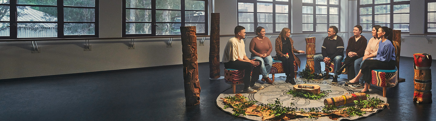 Group of people sitting in a circle, engaged in a yarning circle discussion, sharing stories and experiences