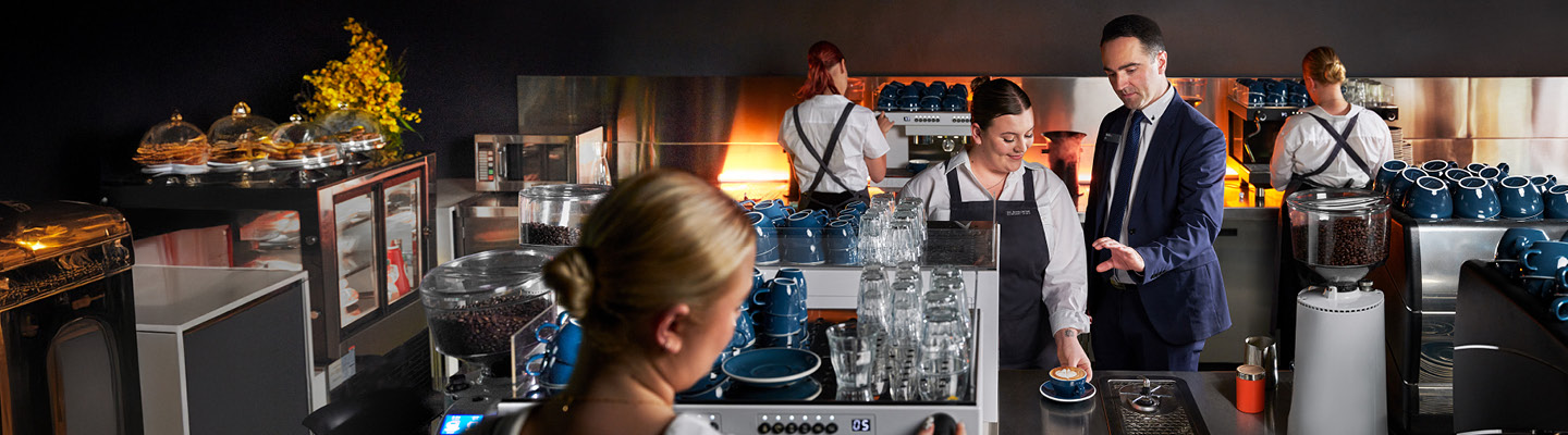 Coffee training session with participants focused on operating a commercial espresso machine