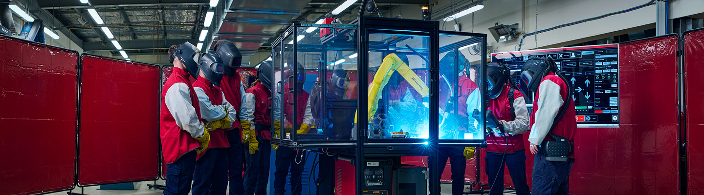A group of individuals wearing protective gear while performing welding tasks in a workshop
