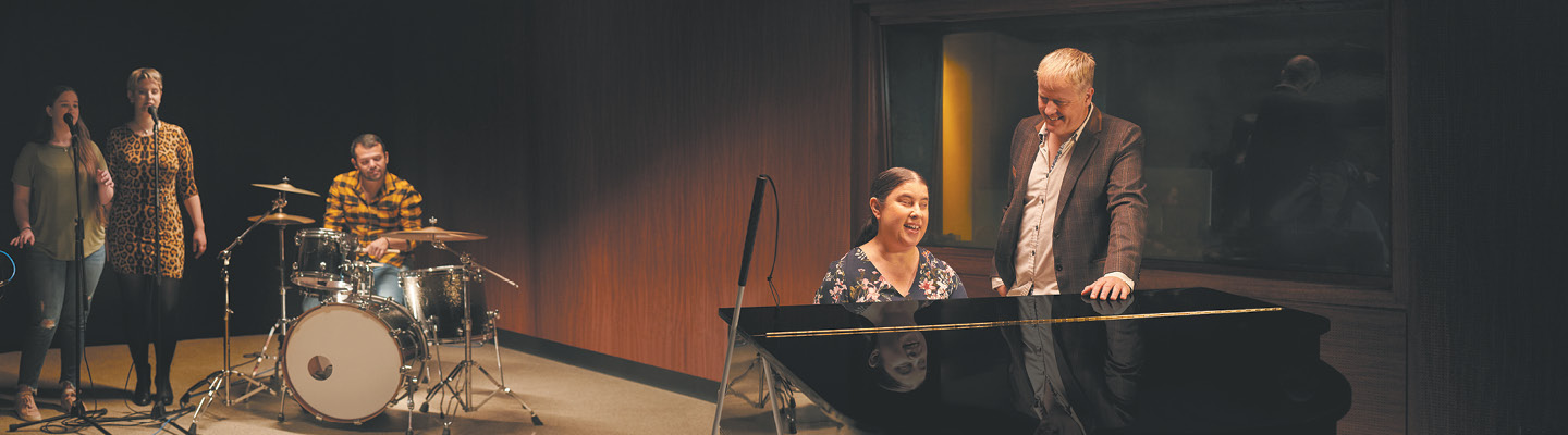 Collaborative music practice session with students performing and an instructor mentoring a piano student.