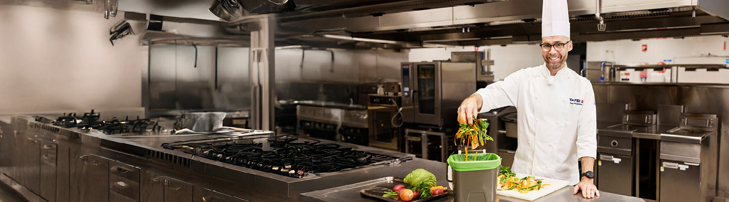 TAFE NSW culinary student practising proper food waste disposal in a commercial kitchen.