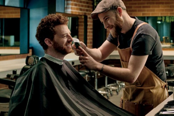 Hands-on barbering training with a TAFE NSW student performing a haircut.