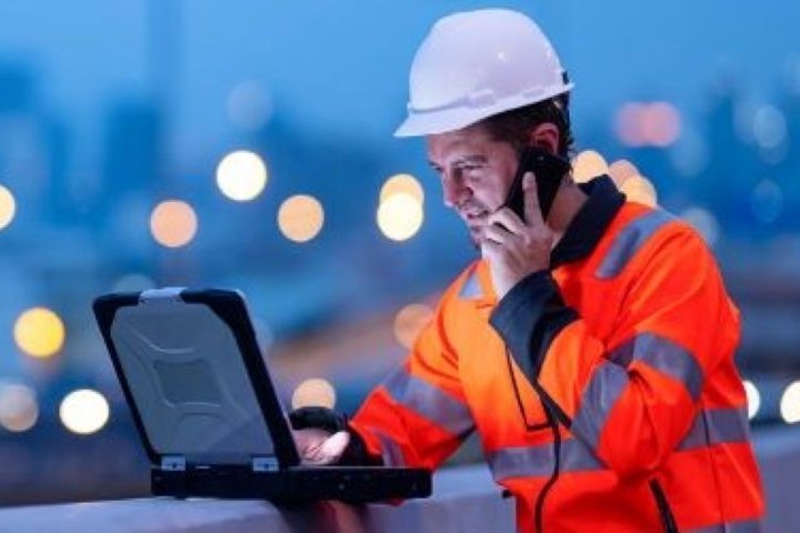 A person in construction career with working phone and laptop