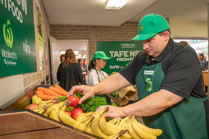 Student arranging fruit in a supermarket training environment.