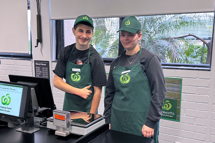 Two Woolworths staff members standing at the checkout counter