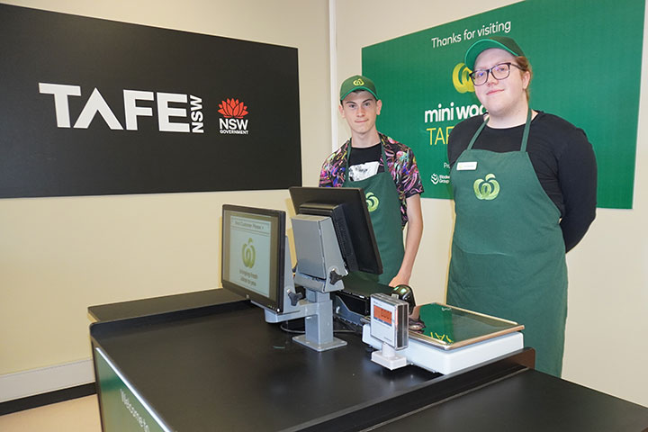 Young students posing for a picture behind a cash register
