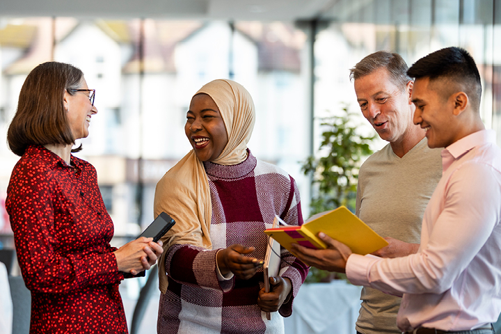 Group of people outside engaging in conversation with notebooks in their hands.