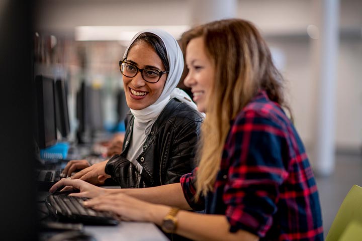 Two young females collaborating on a computer.