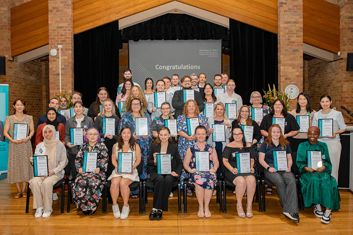 Group of people celebrating a community achievement with a congratulatory banner.